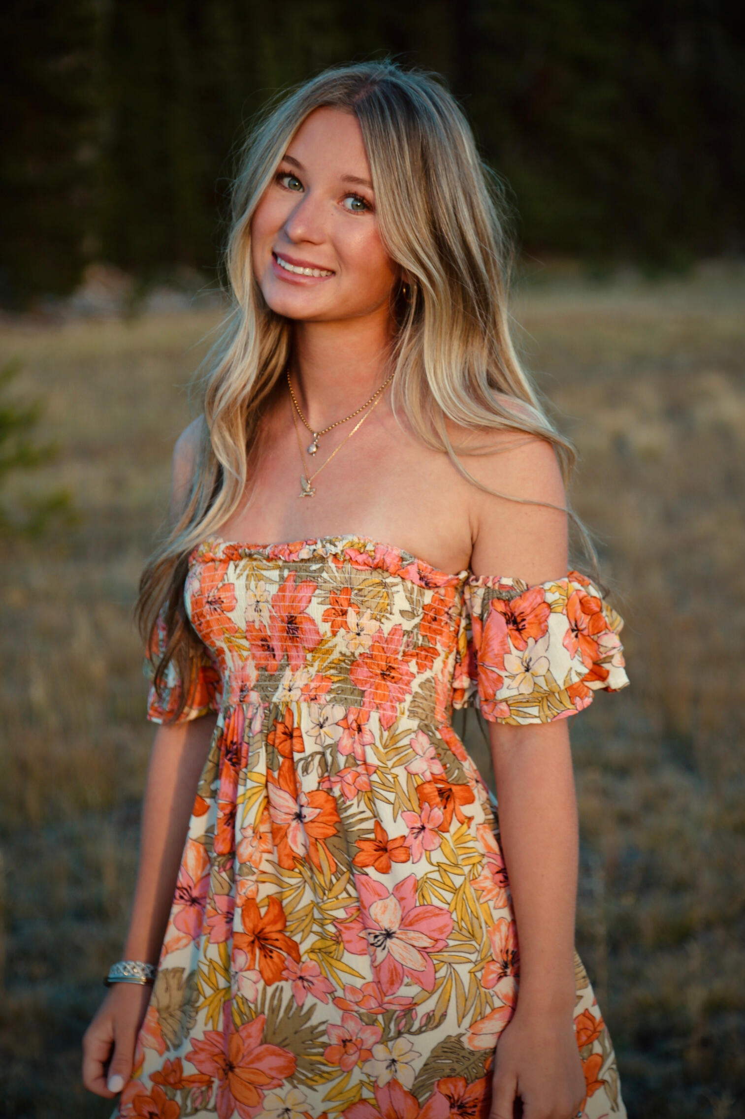 Outdoor editorial portrait of Jada wearing a coral floral dress in warm evening light.